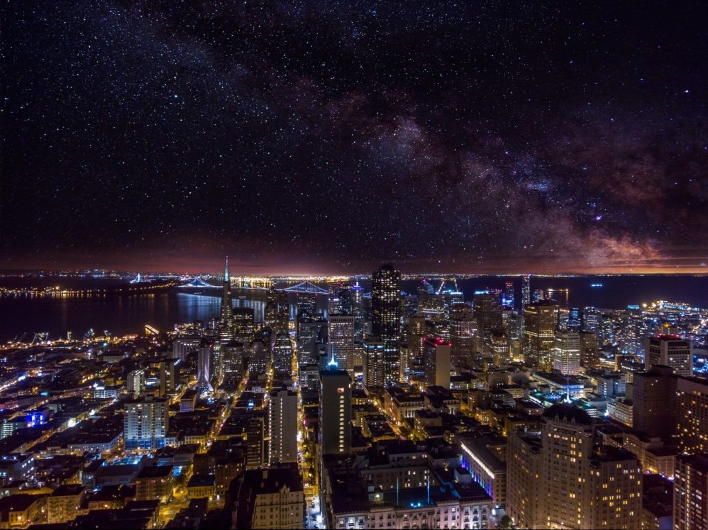 Night city skyline and bay under a starry Milky Way sky